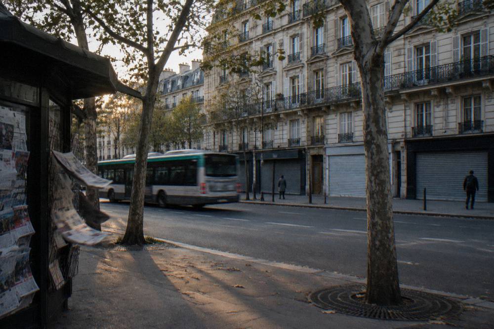 A Paris boulevard in evening light with buses and shuttered shopfronts