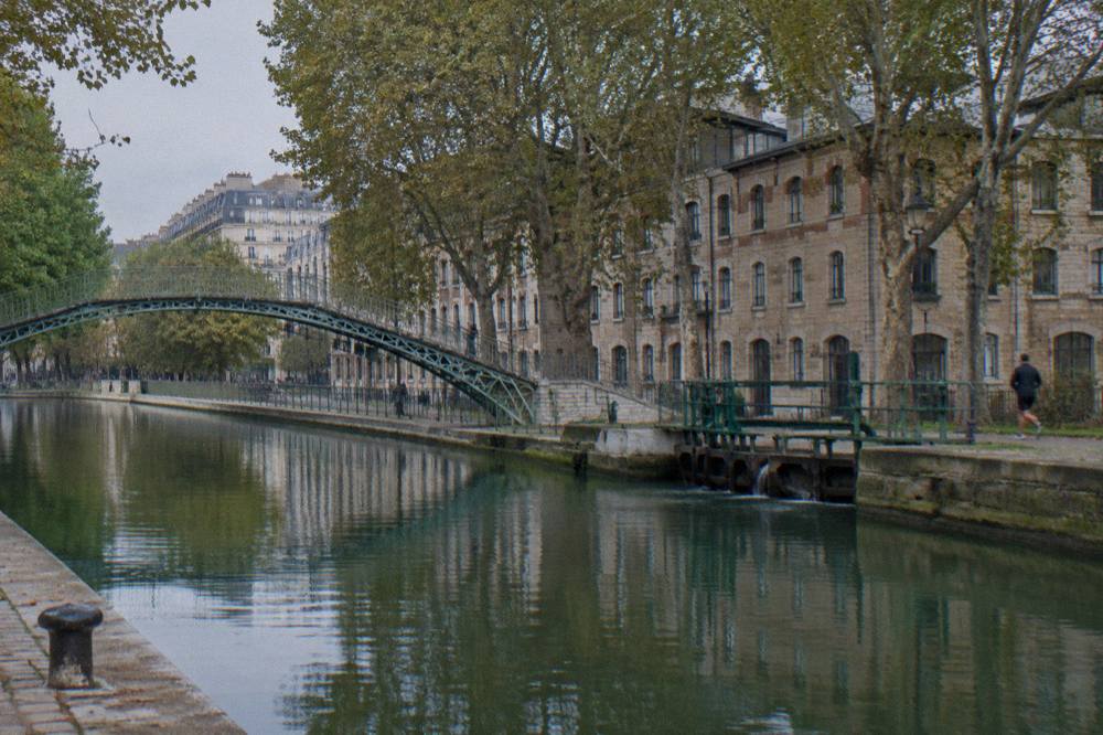 A canal-side street in Paris with plane trees and old stone buildings