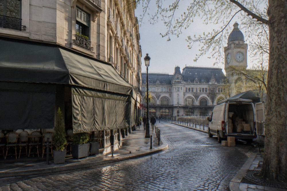 Narrow Paris street in the 10th arrondissement with a canal bridge, cafe awnings and early morning light