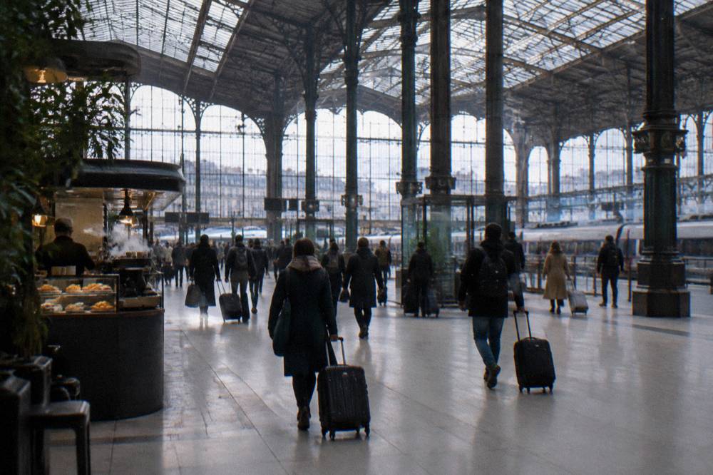Interior of a busy Paris railway station concourse with departure boards and morning travellers with bags