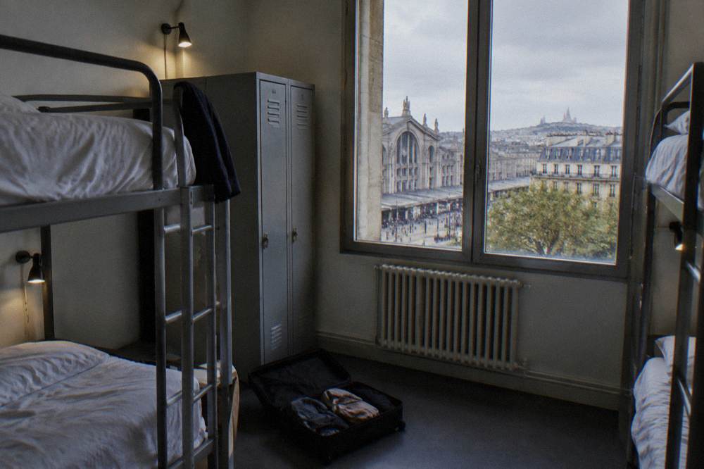Simple bright hostel dorm room with bunk beds, individual reading lights and lockers