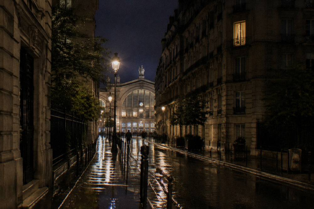 Illuminated facade of a large Paris railway station seen from a quiet street at night