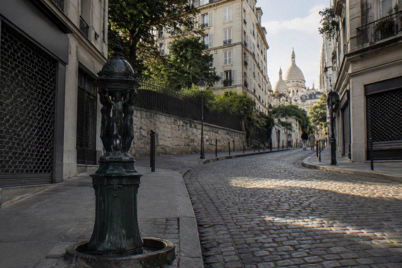 A narrow Paris street lined with old stone buildings and small shop fronts