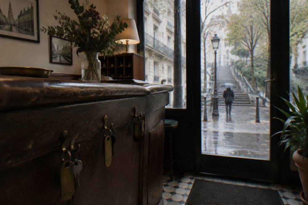 A reception desk in a small Paris hotel with a wooden counter and room keys on hooks