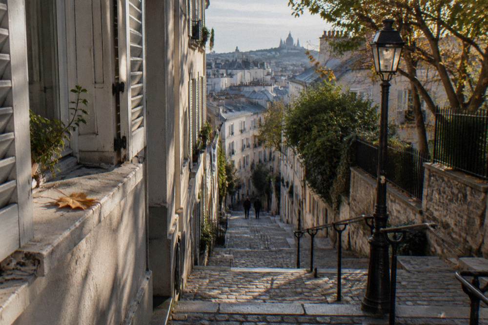 A narrow Montmartre street with stone steps and small hotel shutters in morning light