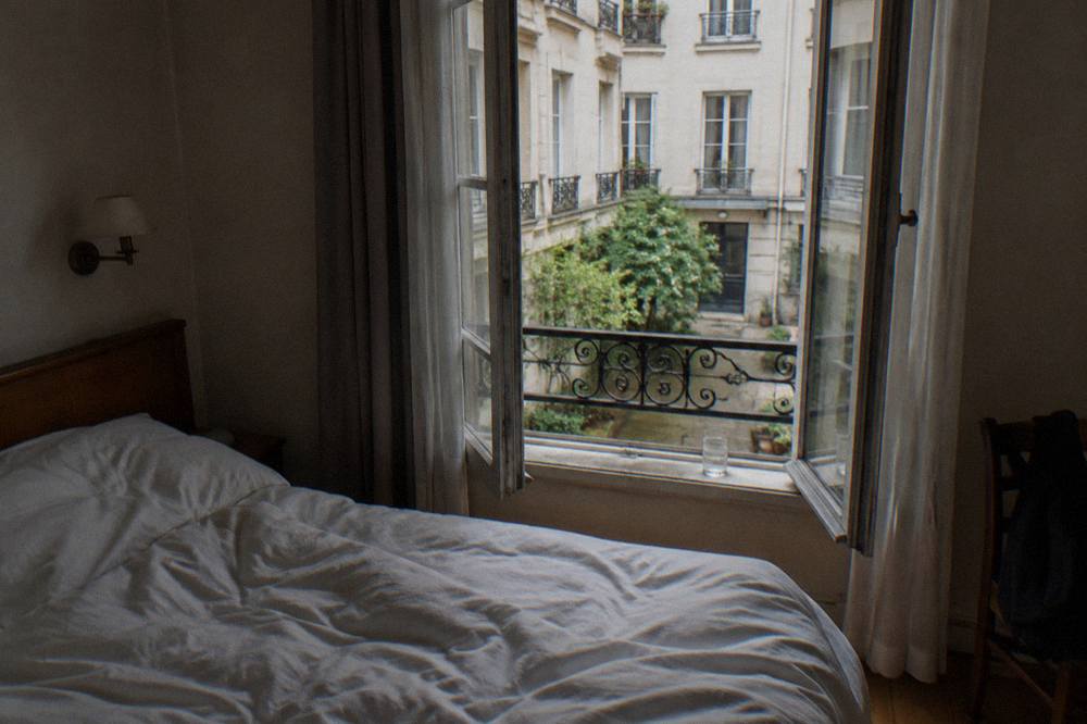 A small Paris hotel room with a double bed and a window onto a courtyard
