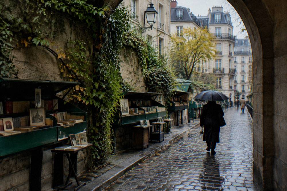 Cobblestone lane in the Latin Quarter with bookshops and a stone archway