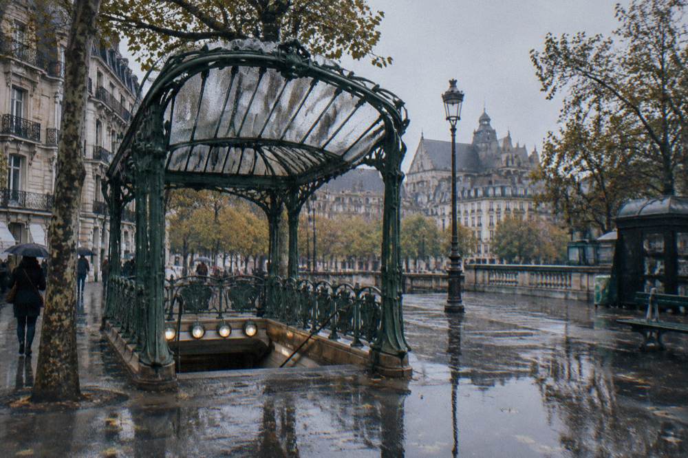 Metro station entrance with a Art Nouveau-style sign on a Paris sidewalk