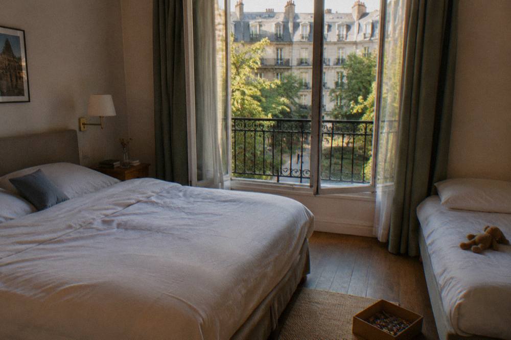A bright family hotel room in Paris with a double bed, a single bed and a window onto a courtyard
