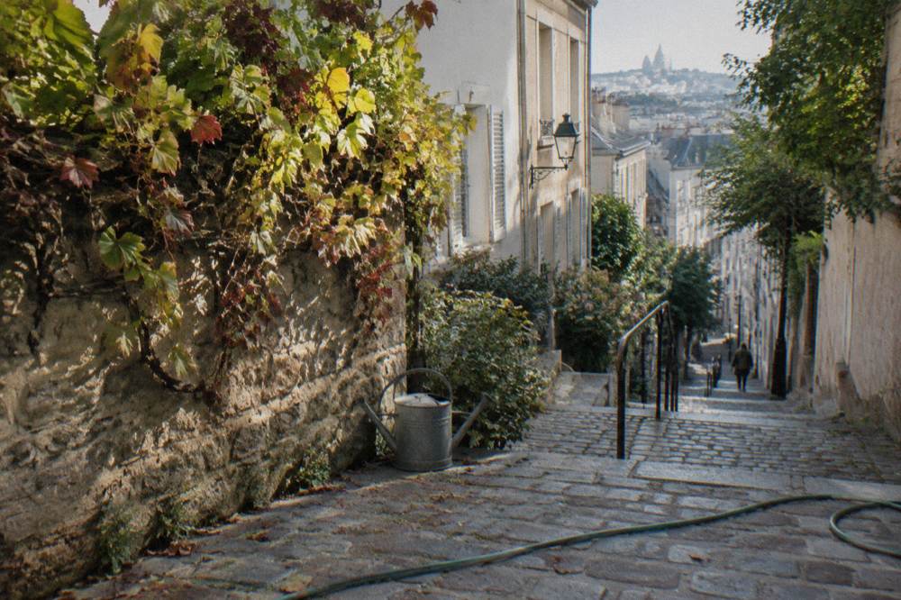 Quiet narrow Montmartre lane with vines and stone walls in morning light
