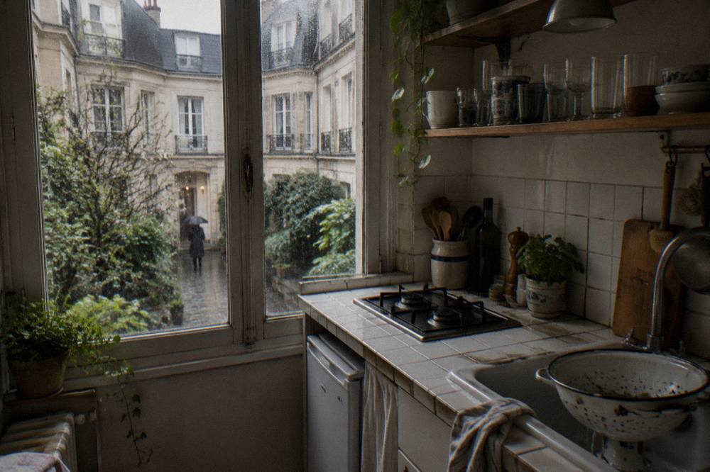 A compact studio apartment kitchen with a small counter, shelves and a window
