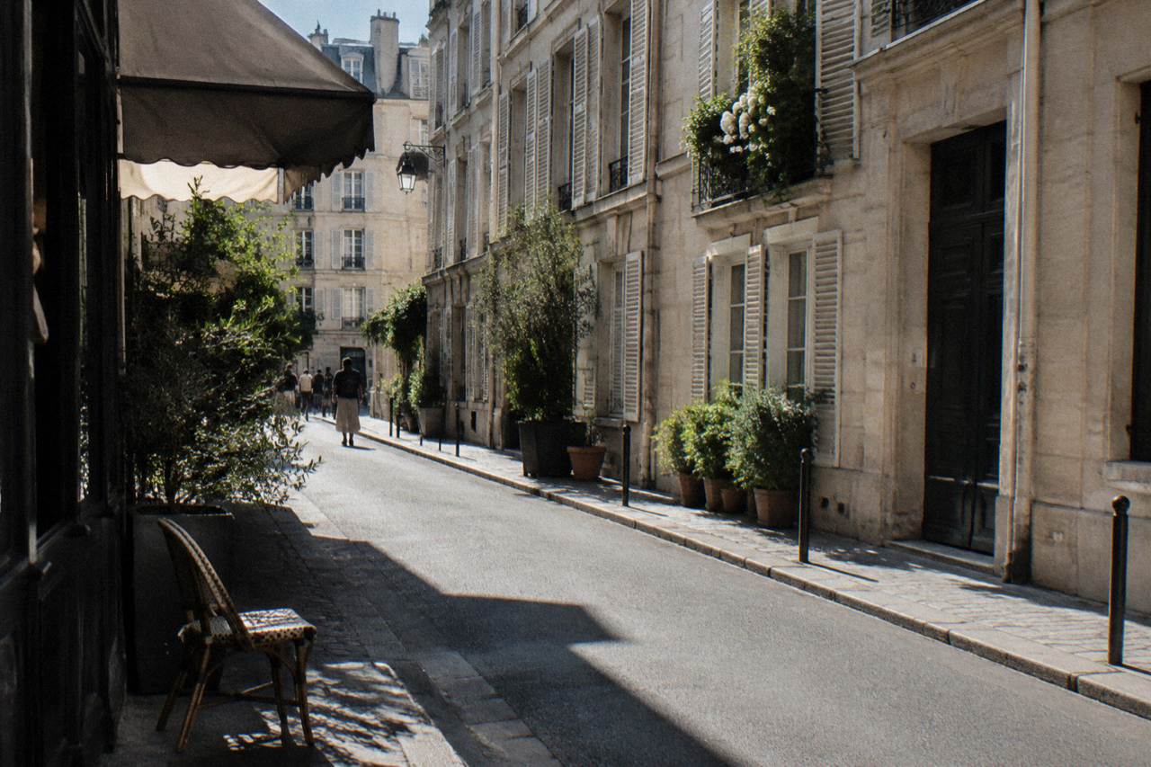A narrow Paris street with cream-colored apartment buildings and shuttered windows