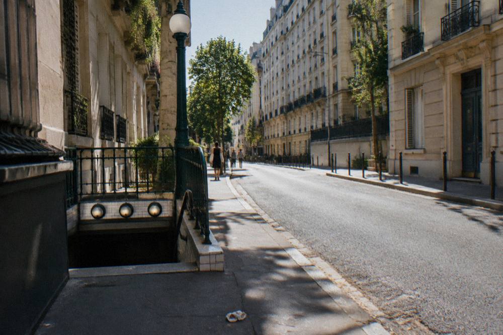 A narrow Paris street with stone facades and a metro sign in view