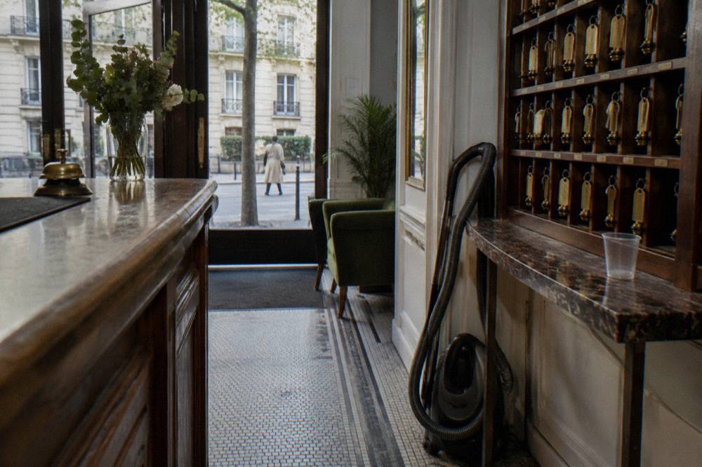A reception desk in a small Paris hotel with a room key rack on the wall behind
