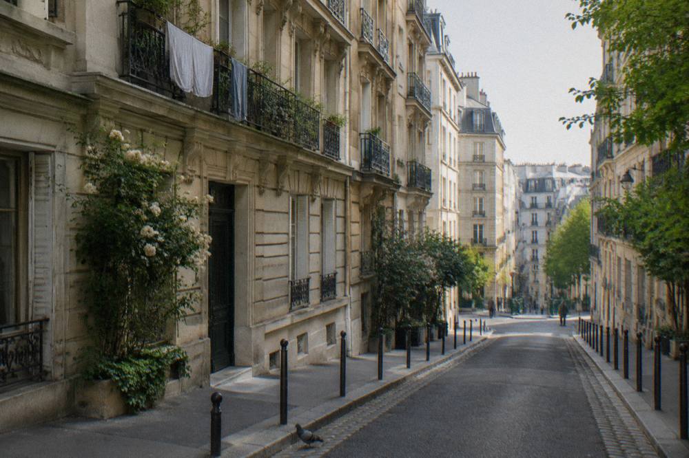 A narrow Paris street with haussmann buildings and a distant metro entrance