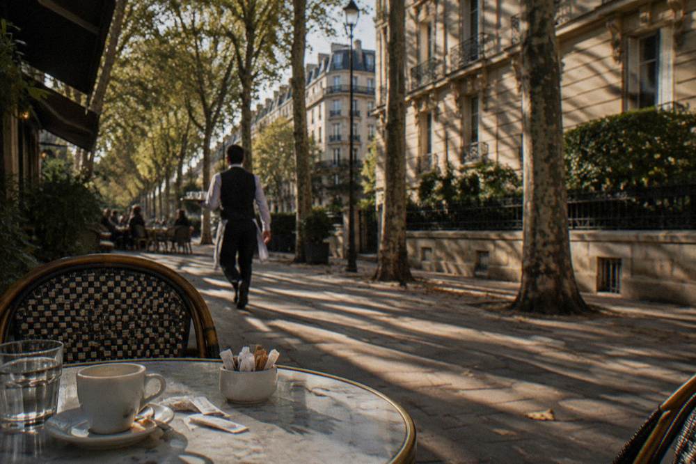 A residential Paris street with cafes and trees in the late afternoon