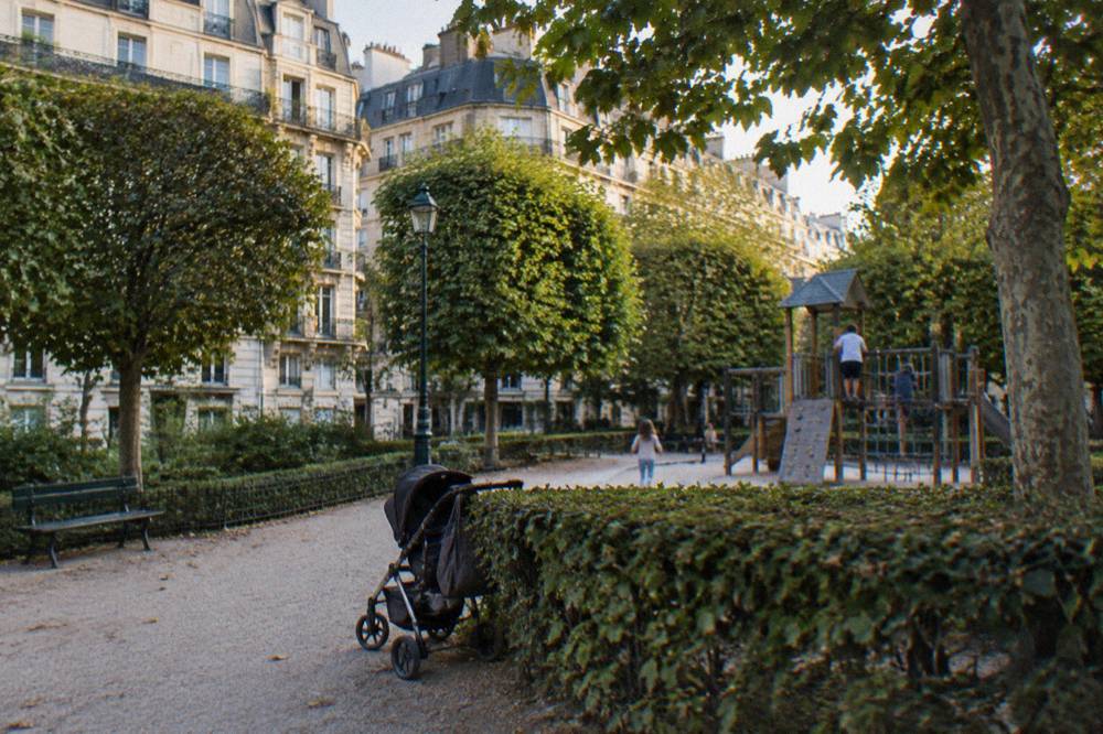 A leafy square in a residential Paris district with benches and a playground