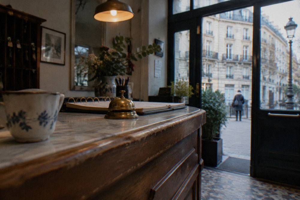 A small hotel reception desk in Paris with a wooden counter and warm lighting