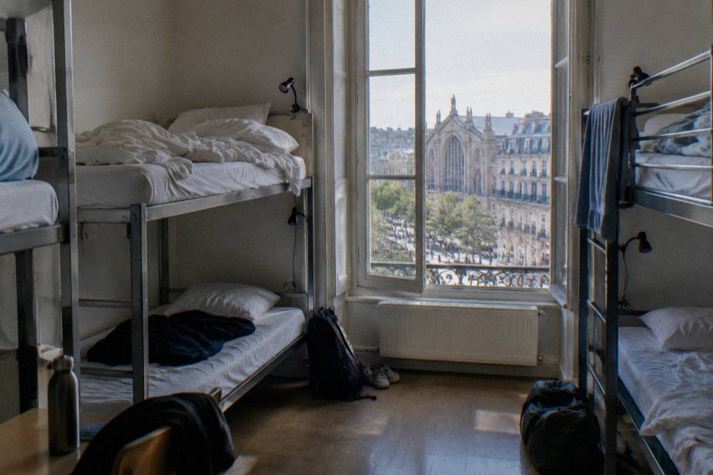 A bright hostel dorm room with bunk beds and individual reading lights