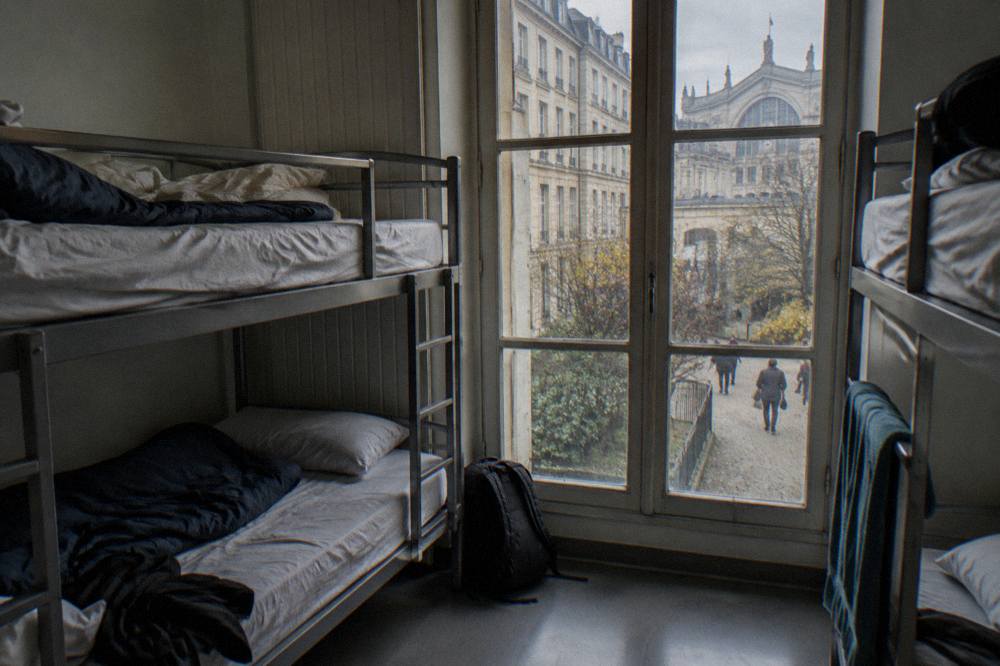 Bunk beds in a simple hostel dorm room with a window onto a Paris courtyard