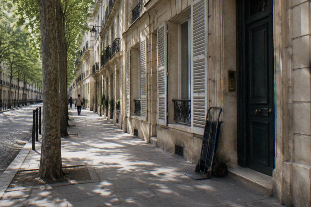 A narrow Paris street in the Marais with stone buildings and shuttered windows