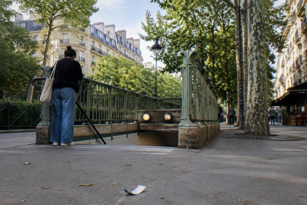 A metro station entrance in Paris with a rider checking the line map