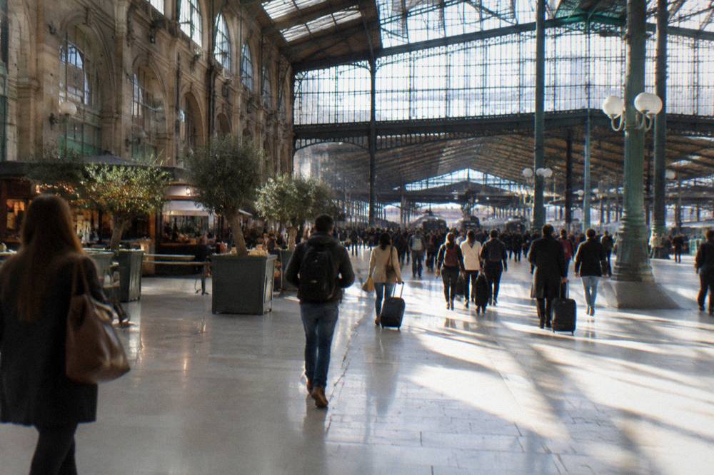 A busy Paris station concourse with departure boards and morning light