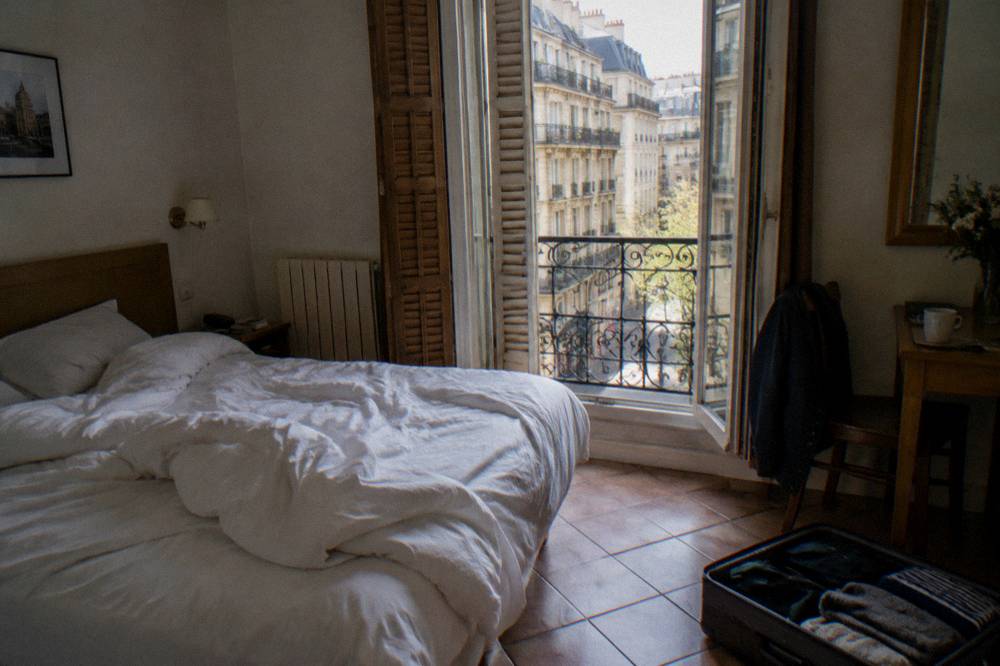 A compact budget hotel room with a double bed and shuttered window