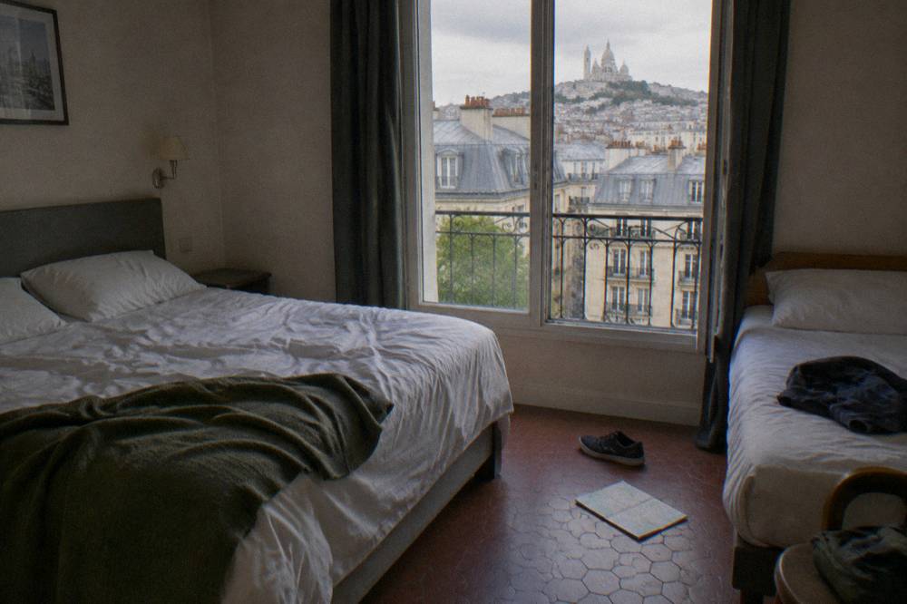 A family-sized hotel room with a double bed and a single bed beside a window