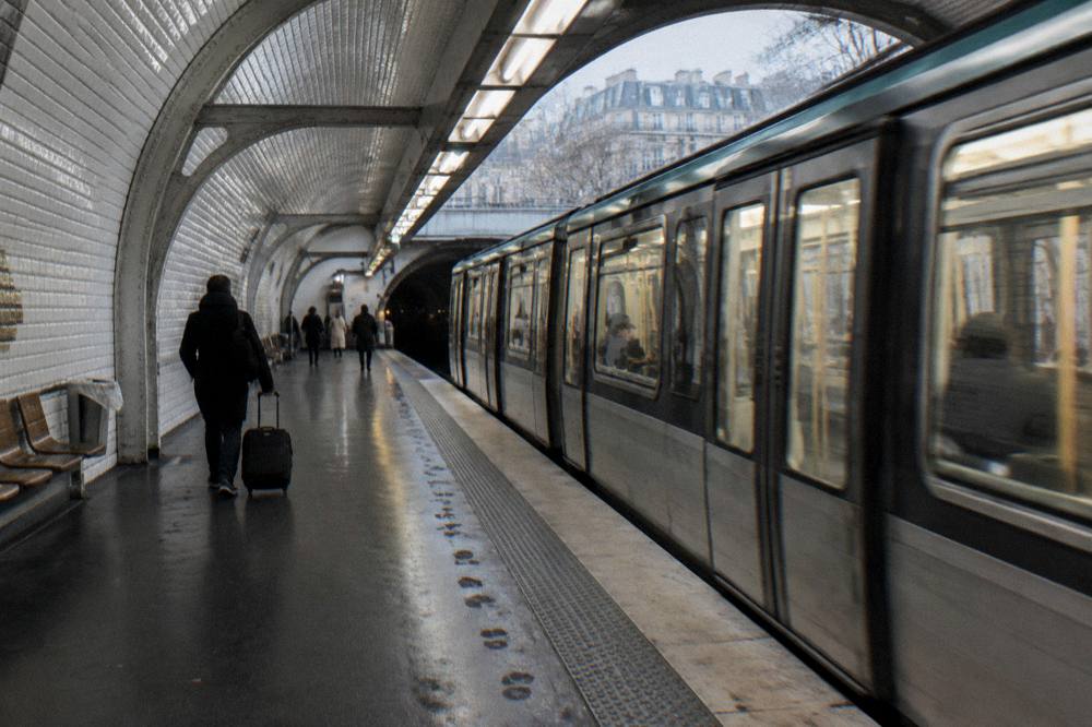 A Paris metro platform with a train arriving and platform signage