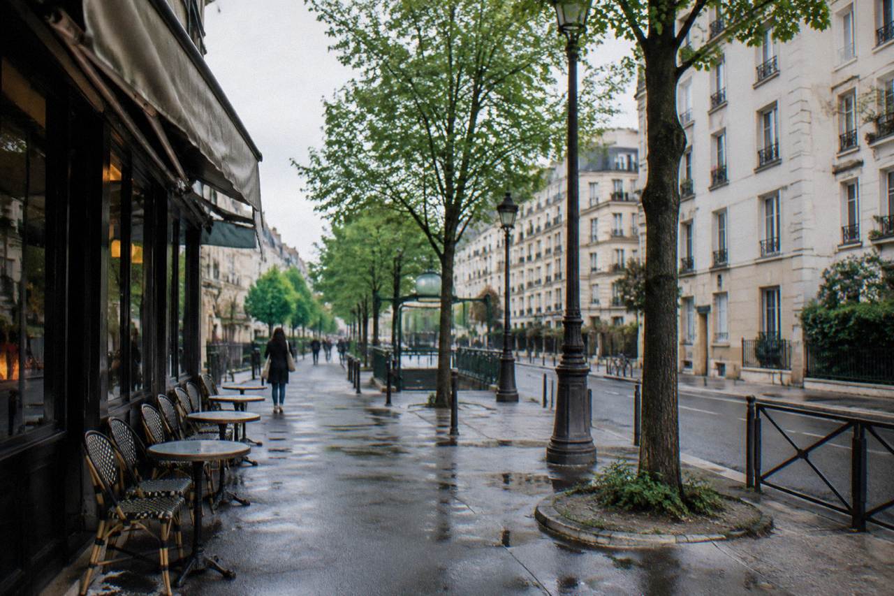 A quiet Paris street with rows of low apartment buildings and a cafe awning under an overcast sky