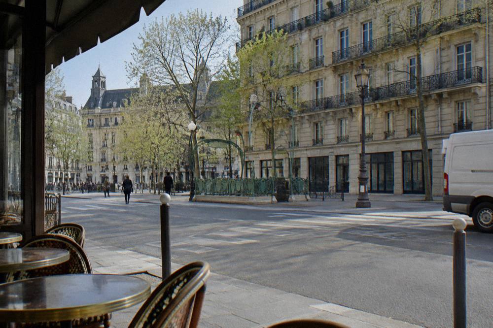 A wide Paris street with Haussmann buildings and a metro entrance in daylight