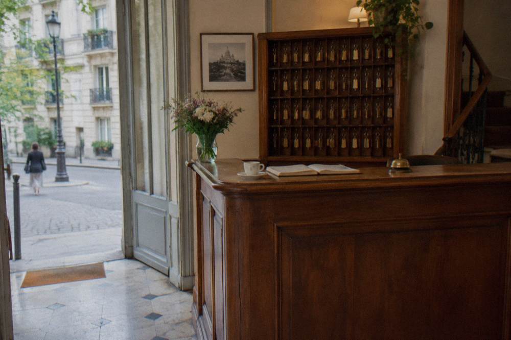 Reception desk of a small Paris hotel with a wooden counter and keys on hooks