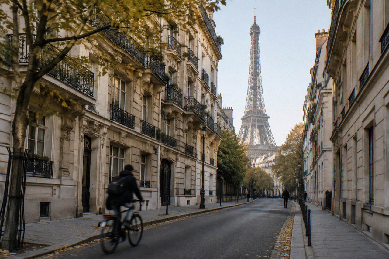 A quiet Parisian street with Haussmann buildings and the top of the Eiffel Tower in the distance