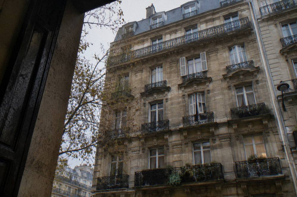 A stone apartment building facade with wrought-iron balconies on a central Paris street