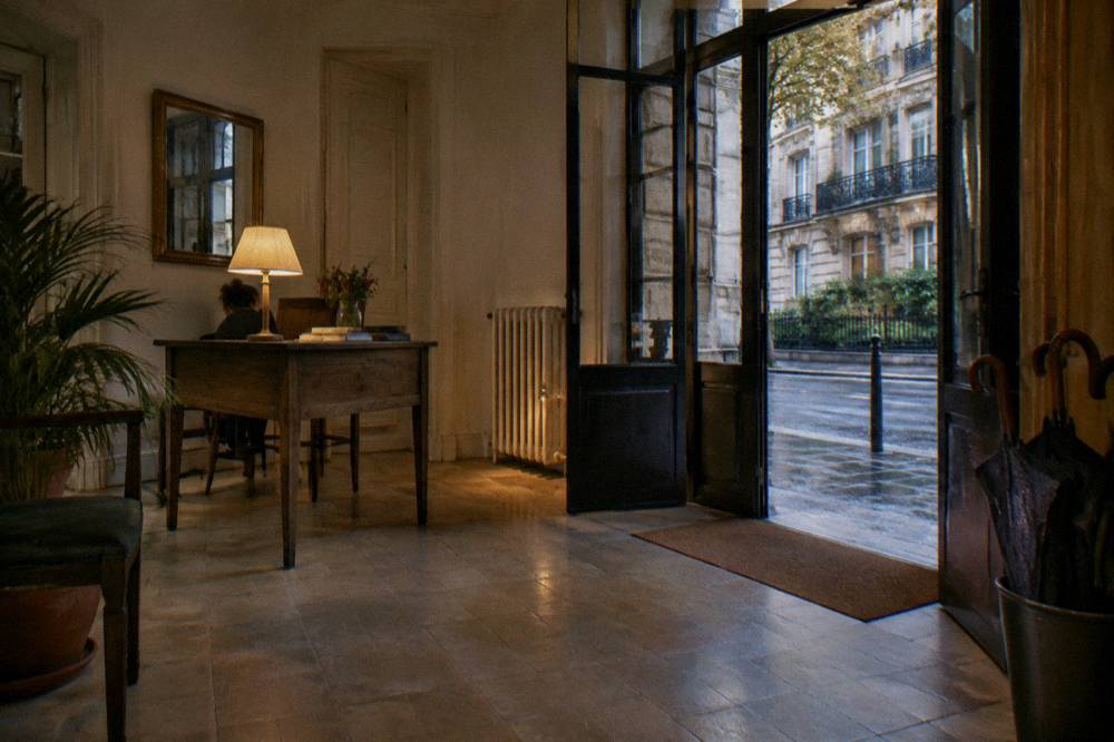 A reception desk and lobby of a small Paris hotel with a stone-tiled floor