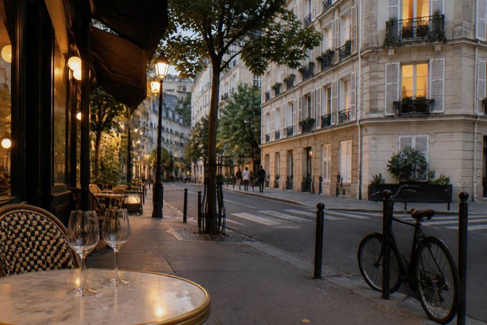 An evening view of a residential street in the 11th arrondissement with lit windows and a corner cafe