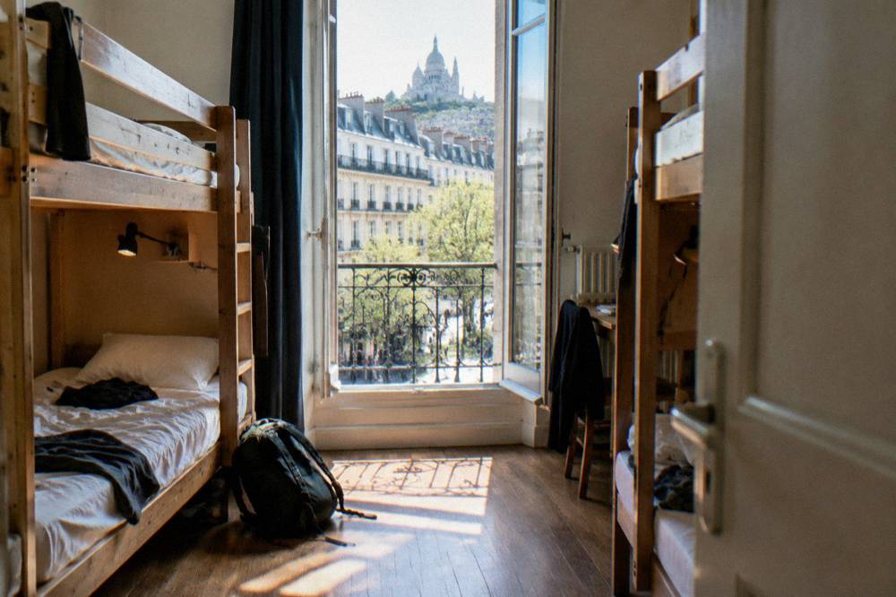 Bunk beds with personal reading lights in a bright hostel dorm room