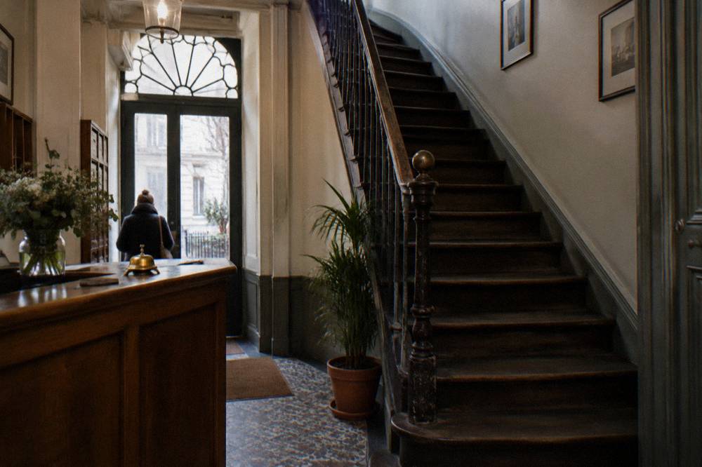 A reception desk and old wooden staircase in a small Paris hotel