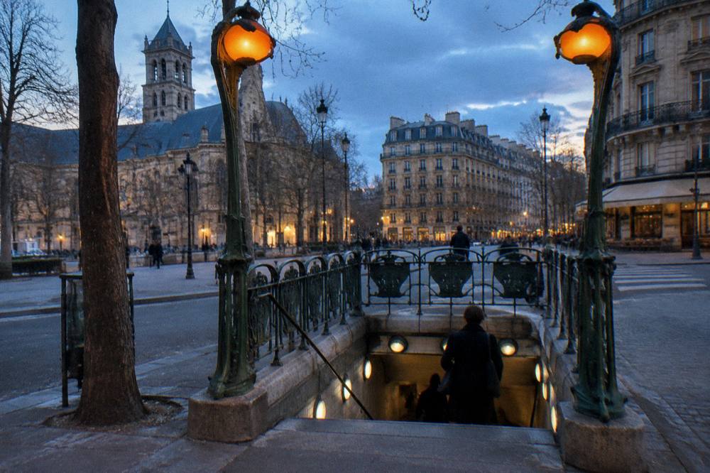A metro entrance with a wrought iron sign on a Paris street