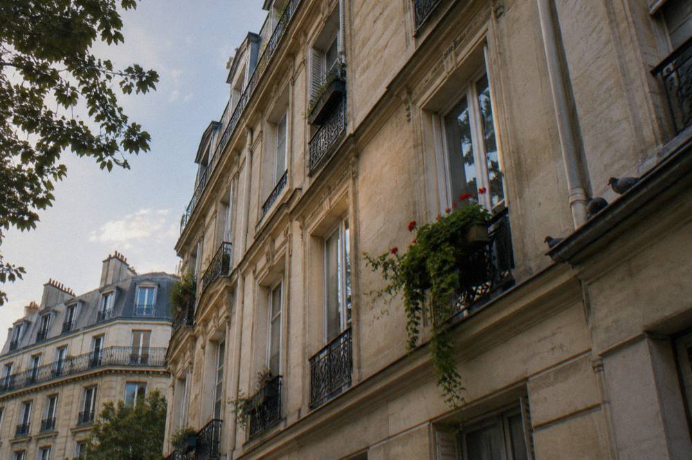 A classic Paris apartment building facade with tall windows and wrought-iron balconies