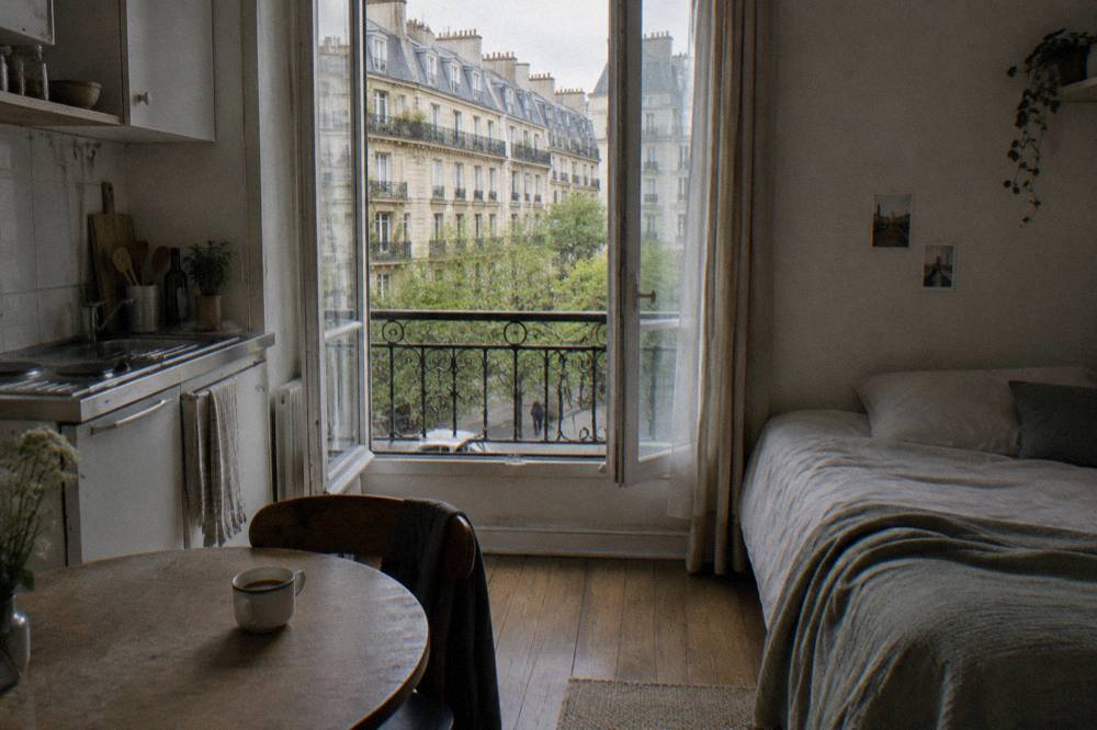 A furnished studio room with a small kitchenette, table and bed