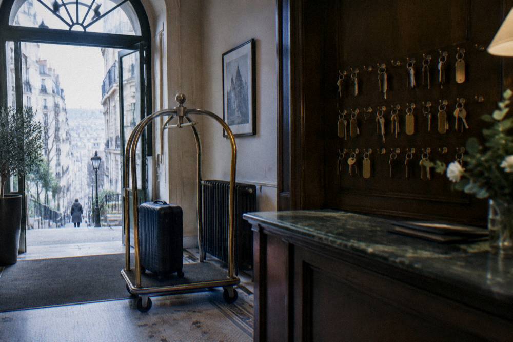 A hotel reception desk in the morning with a luggage trolley and room keys on hooks