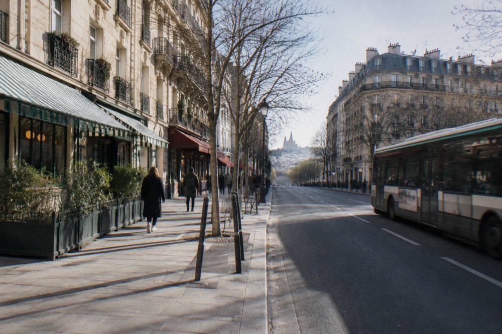 A wide Paris boulevard in the 18th arrondissement lined with apartment buildings and shop awnings