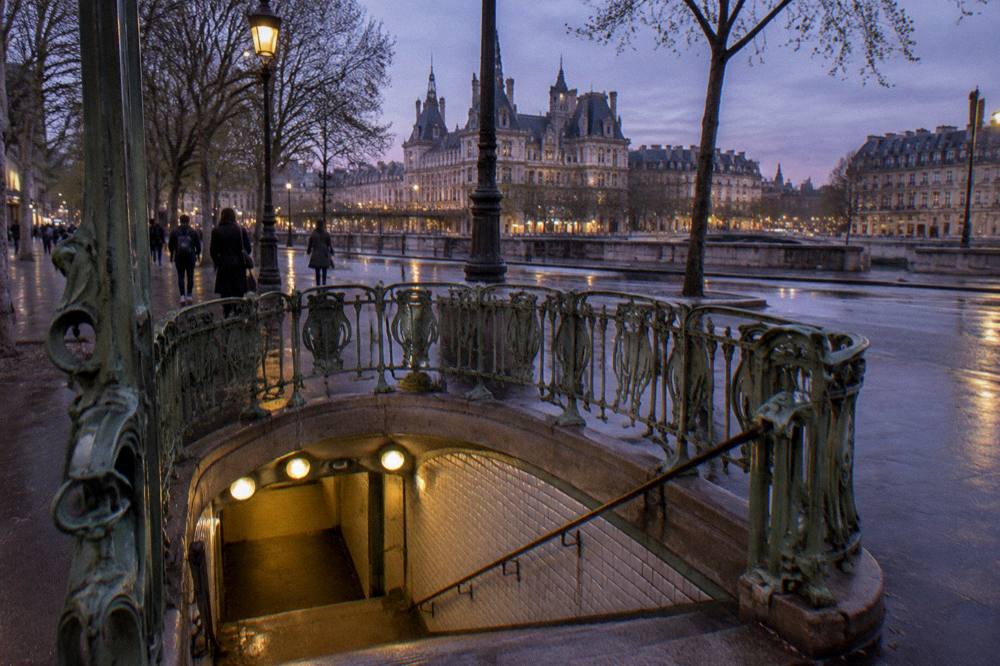 A Paris metro station entrance with its curved sign and stairwell descending to the platform