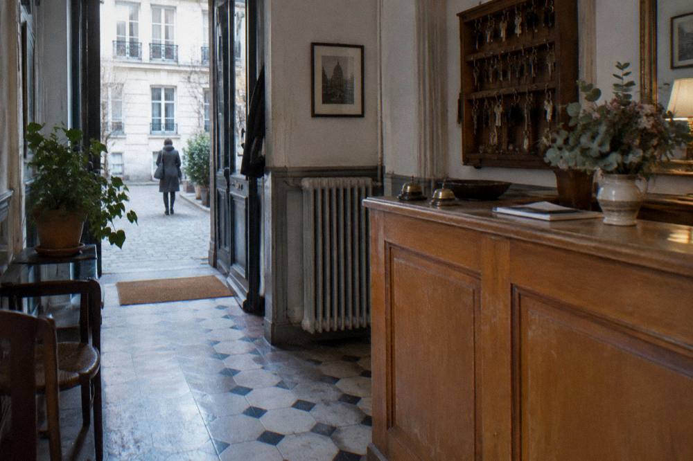 A reception desk with wooden counter and key rack in a small Paris accommodation entrance hall