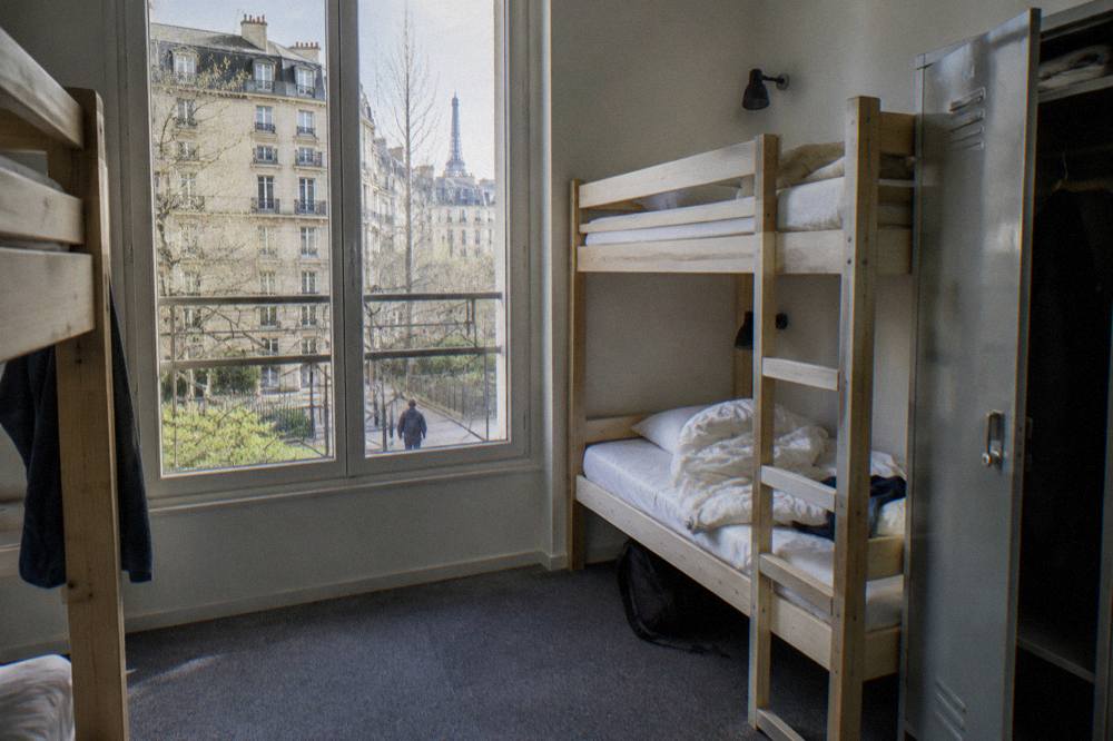 A hostel dorm room with wooden bunk beds and individual reading lights