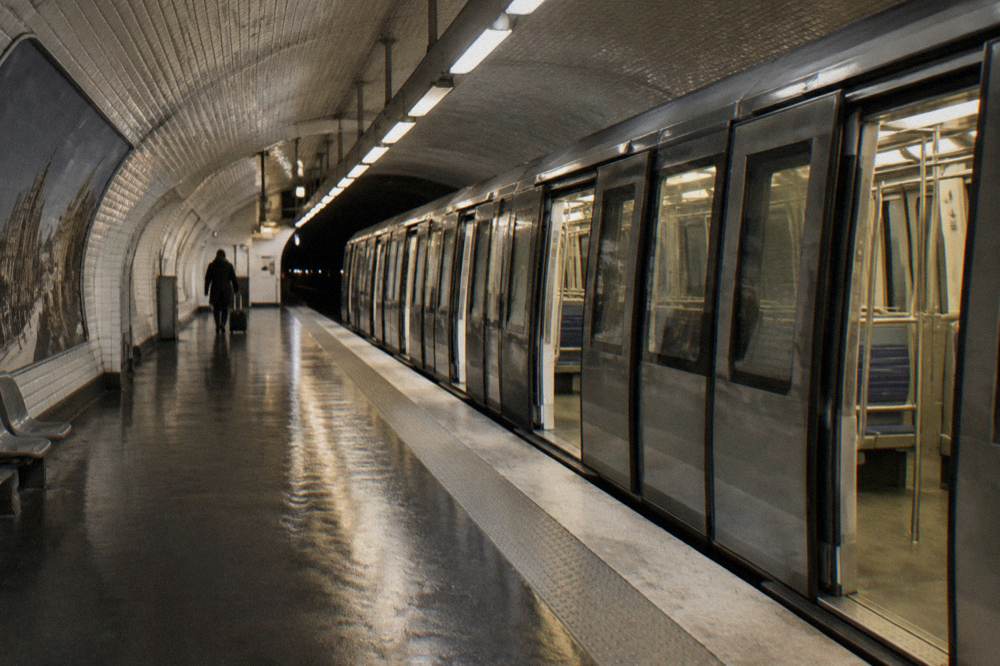A Paris metro platform with a train arriving and platform signs overhead