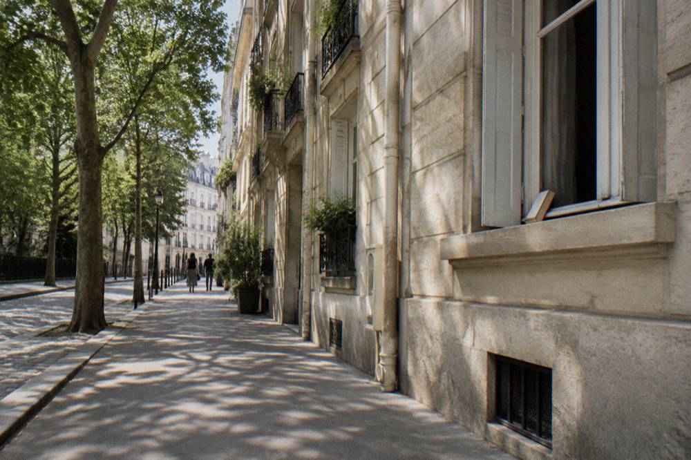 A Parisian street corner in the Marais with stone facades and balconies
