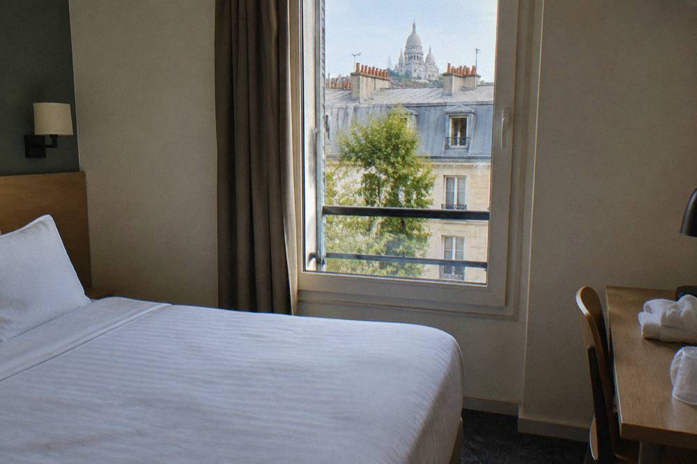 A tidy double hotel room with a city window in Paris